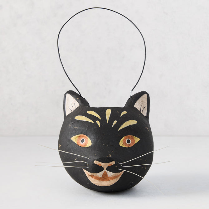 Distressed black papier-mâché cat candy bucket with gold accents, white whiskers, and a wire handle.