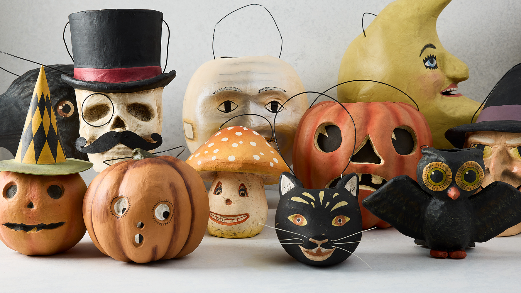Distressed black cat papier-mâché Halloween candy bucket with hand-painted features, among other vintage-style decorations.