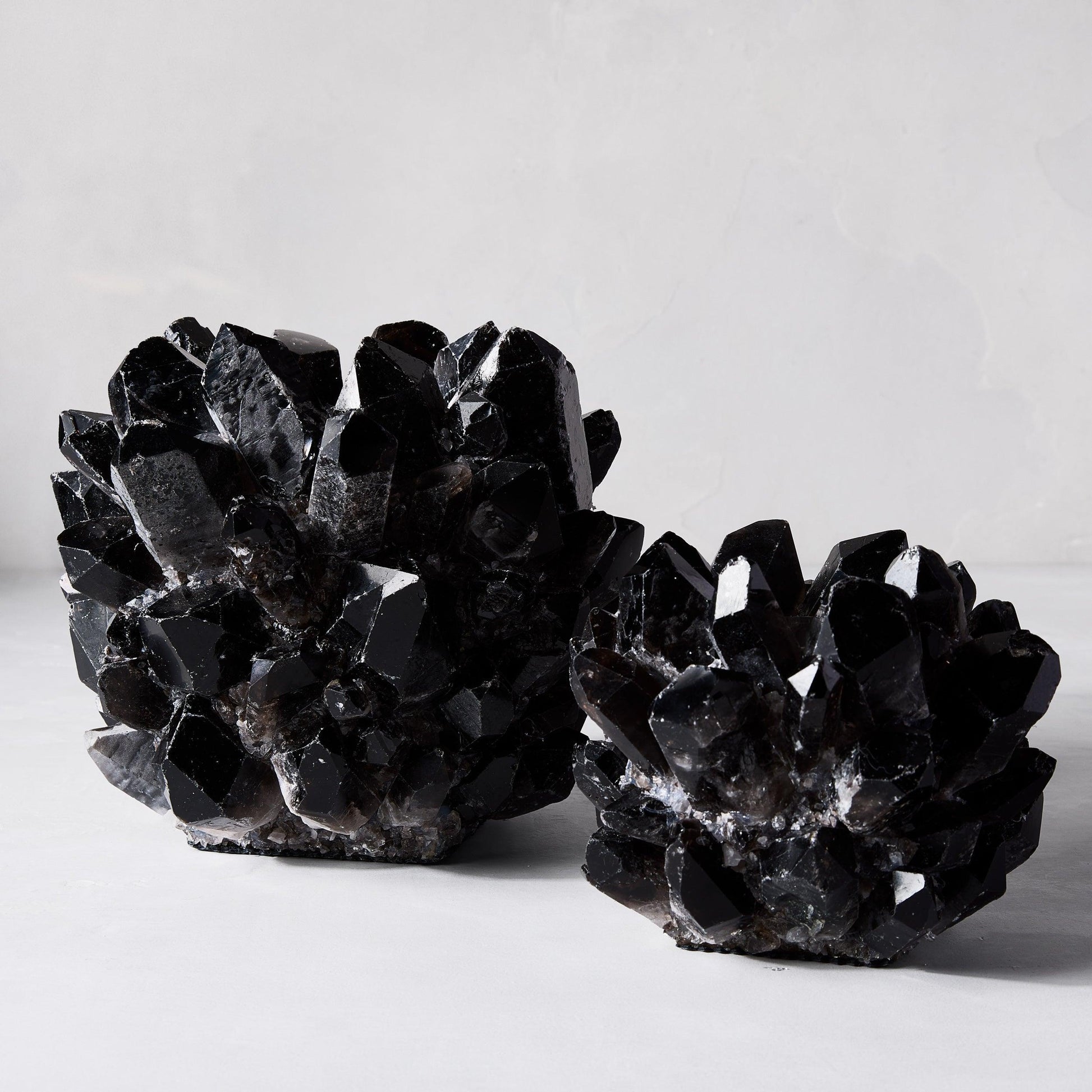 Two Black Grande Quartz Votive Candle Holders, one large and one smaller, made of genuine dark quartz crystal.