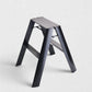Hudson Grace black Hasegawa Lucano 2-step ladder with a matte finish, grooved treads, and a slim folding design.
