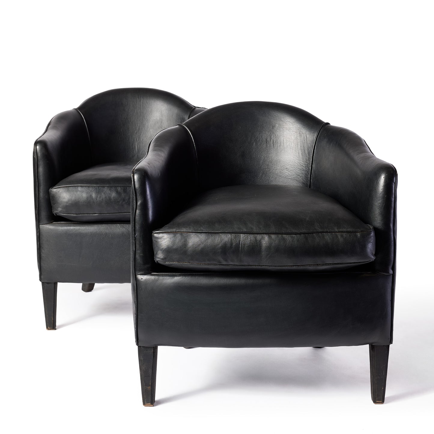 Set of two vintage art deco club armchairs upholstered in smooth black leather with arched backs and ebonized wood legs.