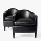 Set of two vintage art deco club armchairs in smooth black leather with scalloped arched backs and ebonized wood legs.