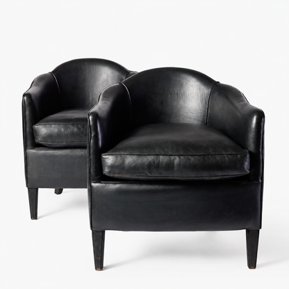 Set of two vintage art deco club armchairs in smooth black leather with scalloped arched backs and ebonized wood legs.