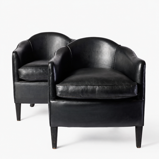 Set of two vintage art deco club armchairs in smooth black leather with scalloped arched backs and ebonized wood legs.
