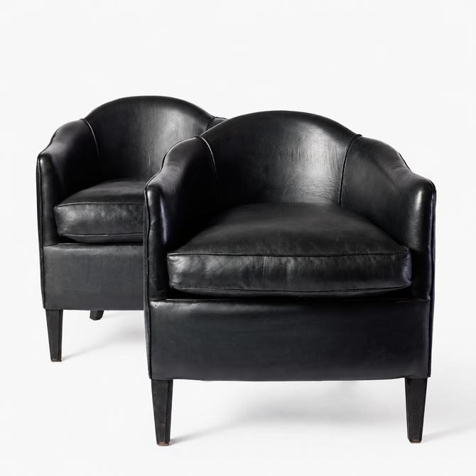 Set of two vintage art deco club armchairs in smooth black leather with scalloped arched backs and ebonized wood legs.
