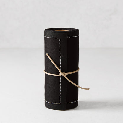 Black cotton cocktail napkin roll with white dotted border, tied with twine.