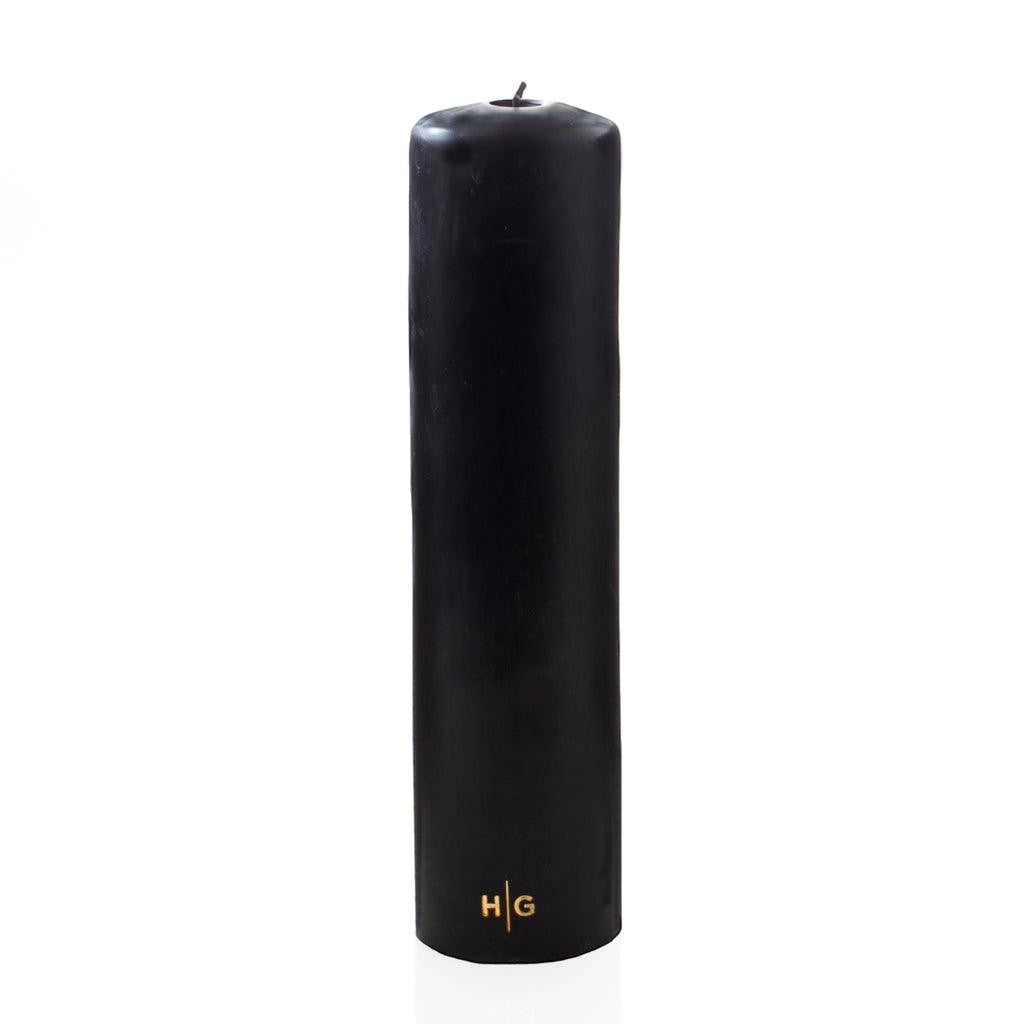 HG Black Unscented Pillar Candle, 3"x12", with gold HG logo, on a white background.