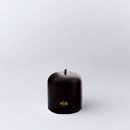 HG Black 3"x3" unscented pillar candle with gold embossed HG logo and oversized cotton wick.