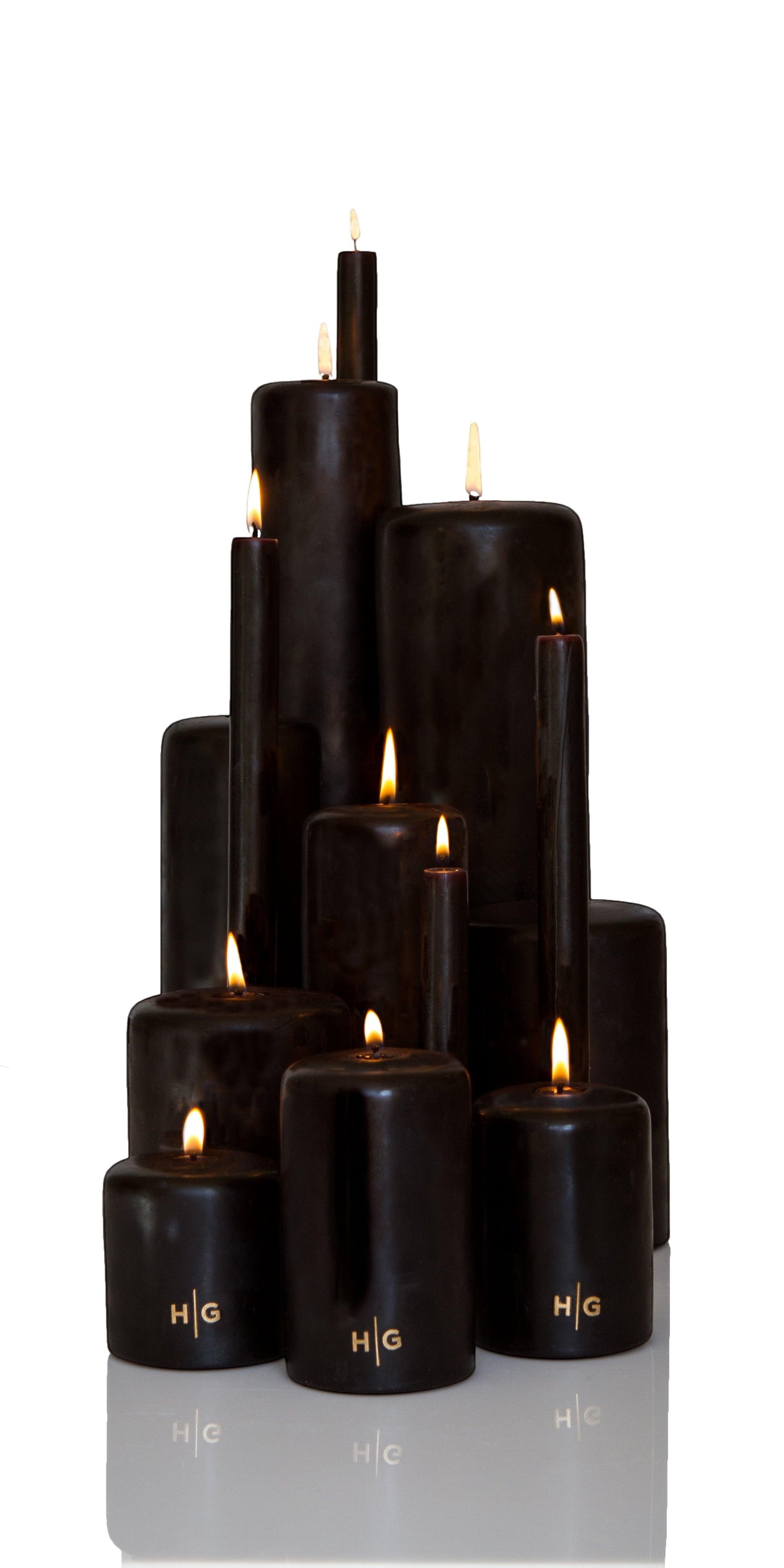 HG Black Unscented Pillar Candles, various sizes, with gold HG logo, burning wicks.