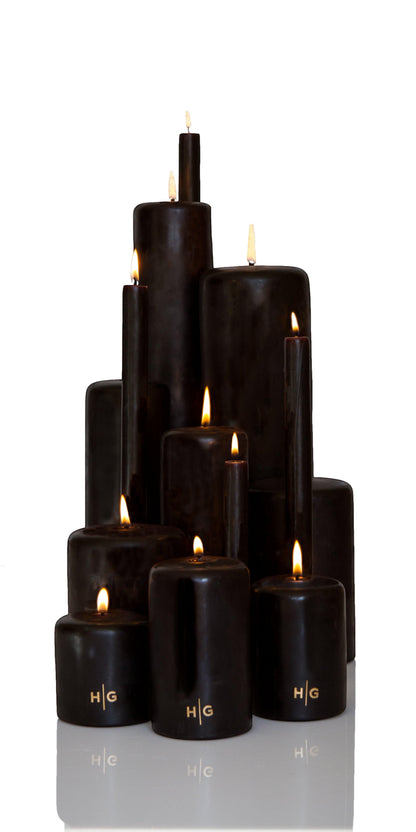 HG Black Unscented Pillar Candles, various sizes, with gold HG logo, burning wicks.