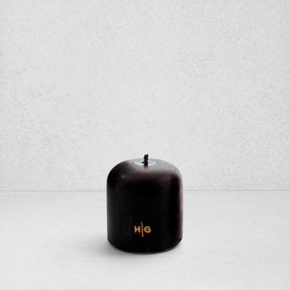 Hudson Grace black unscented pillar candle with gold HG logo and oversized cotton wick on a white background