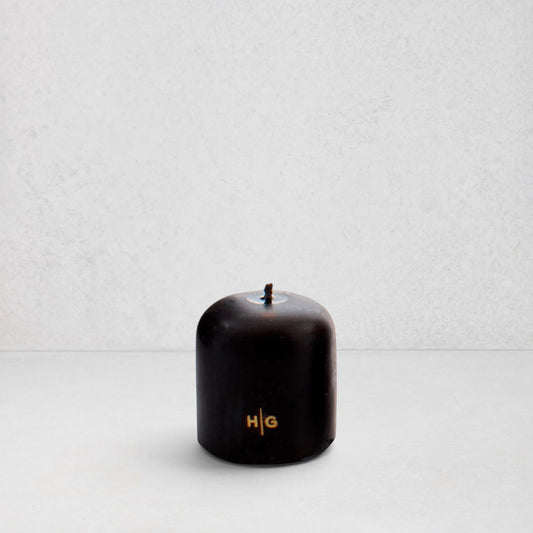 Hudson Grace black unscented pillar candle with gold HG logo and oversized cotton wick on a white background