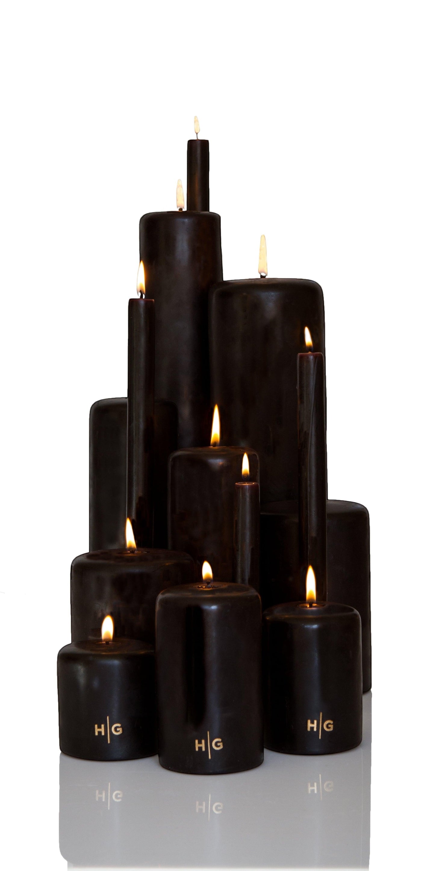 Hudson Grace black unscented pillar candles, various sizes, with gold HG logo, burning wicks.