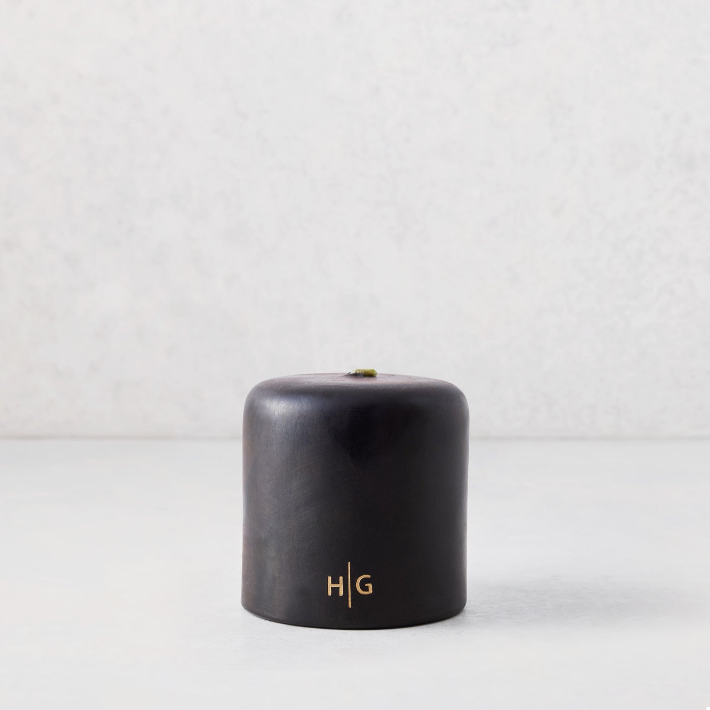 4"x4" black unscented pillar candle with gold HG logo, hand-dipped paraffin and amber resin.