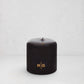 HG Black Unscented Pillar Candle, 4"x4", with gold embossed HG logo and oversized cotton wick.
