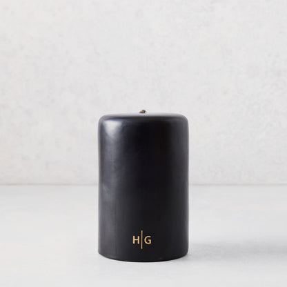 4x6 inch black hand-dipped pillar candle with a gold HG logo, made from paraffin and amber resin.
