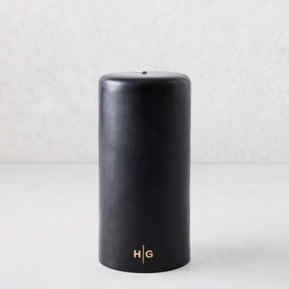 4x8 inch black hand-dipped pillar candle with gold HG logo and cotton wick.
