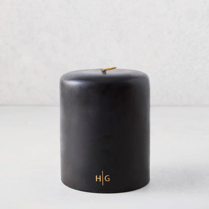 5x6 inch black hand-dipped pillar candle with gold HG logo and cotton wick.