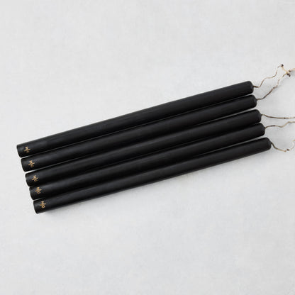 Set of five 15-inch black hand-dipped taper candles with gold HG logo and cotton wicks on a white background.