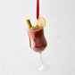 Hand-painted glass Bloody Mary Christmas ornament with celery, olives, and lemon slice garnish on a red ribbon.