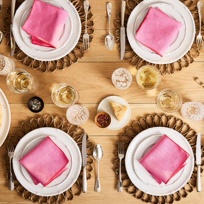 Bloom Woven Abaca Placemat, 15"Dia, natural brown, floral shape, under white plates with pink napkins.