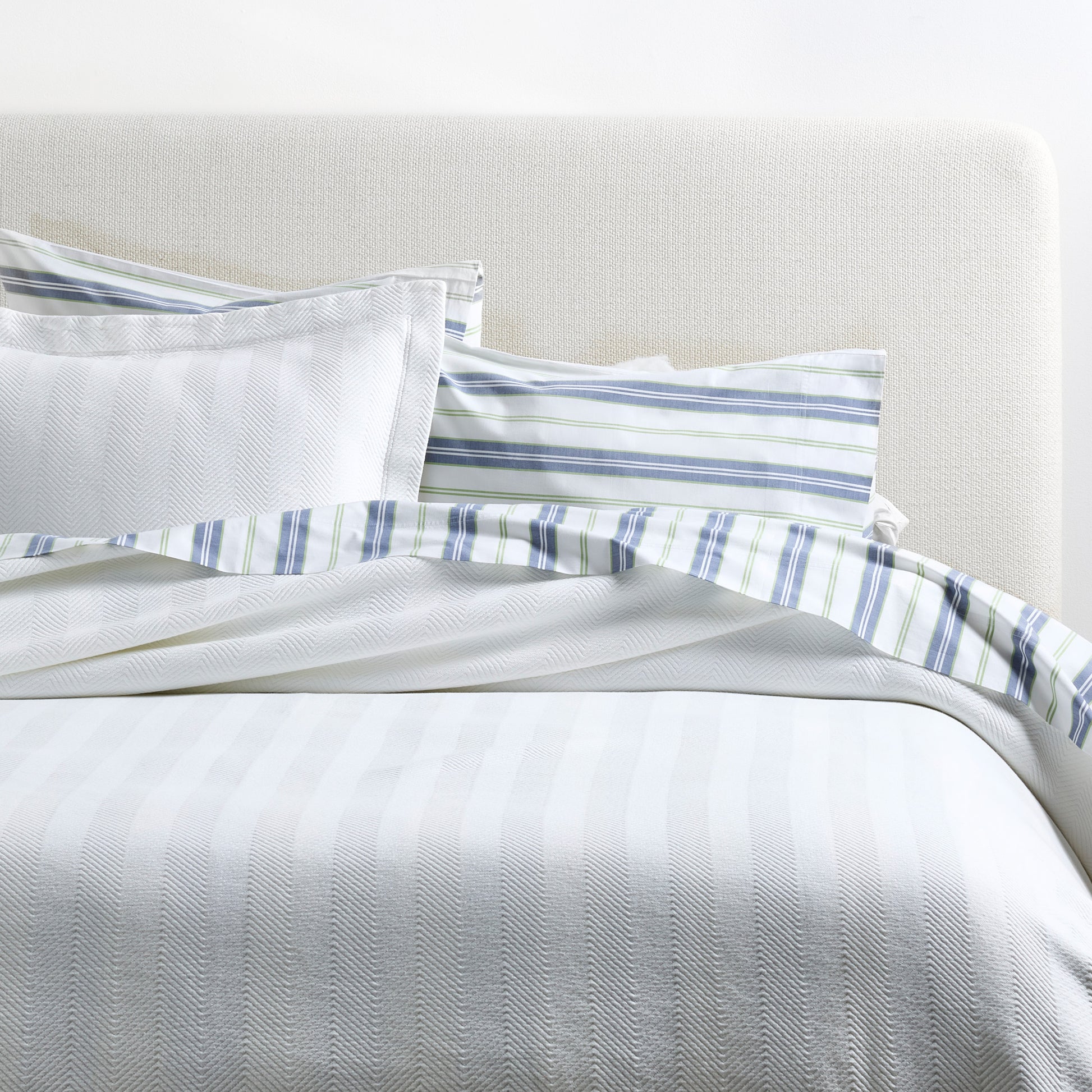 Blue and green multi-stripe percale sheet set with a white herringbone duvet and pillow shams.