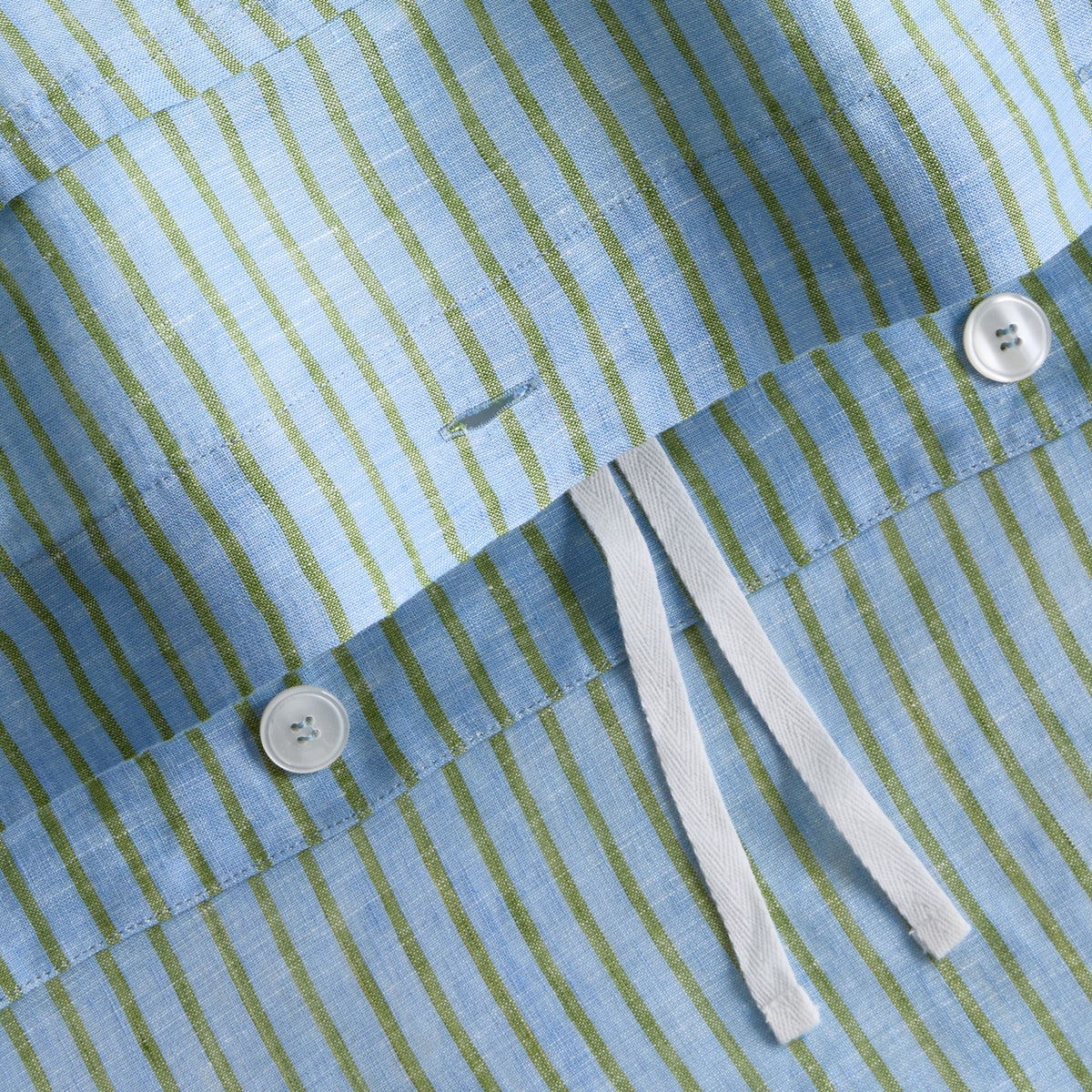 Blue and green striped washed linen duvet cover with white button closures and fabric ties.