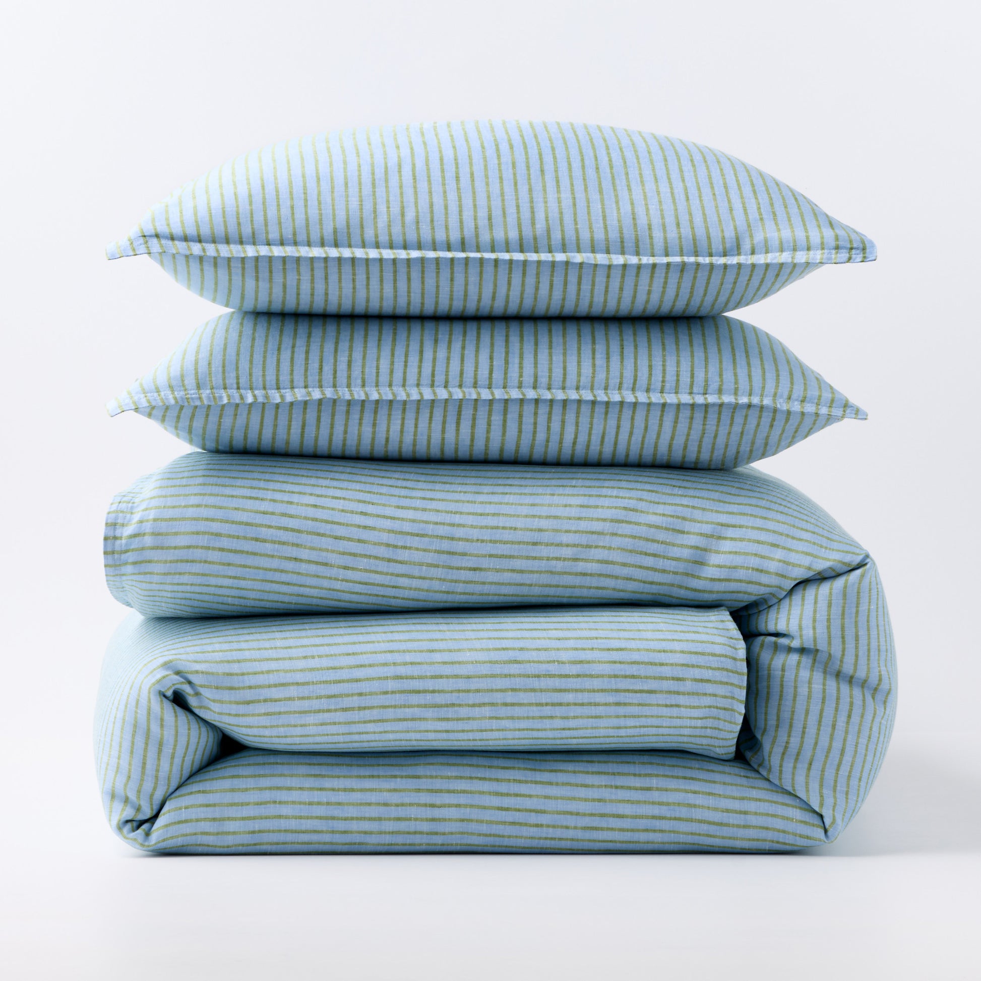 Stacked blue and green striped European washed linen duvet and two shams on a white background.
