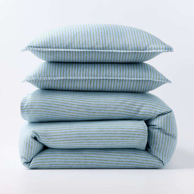 Stacked blue and green striped European washed linen duvet and two shams on a white background.