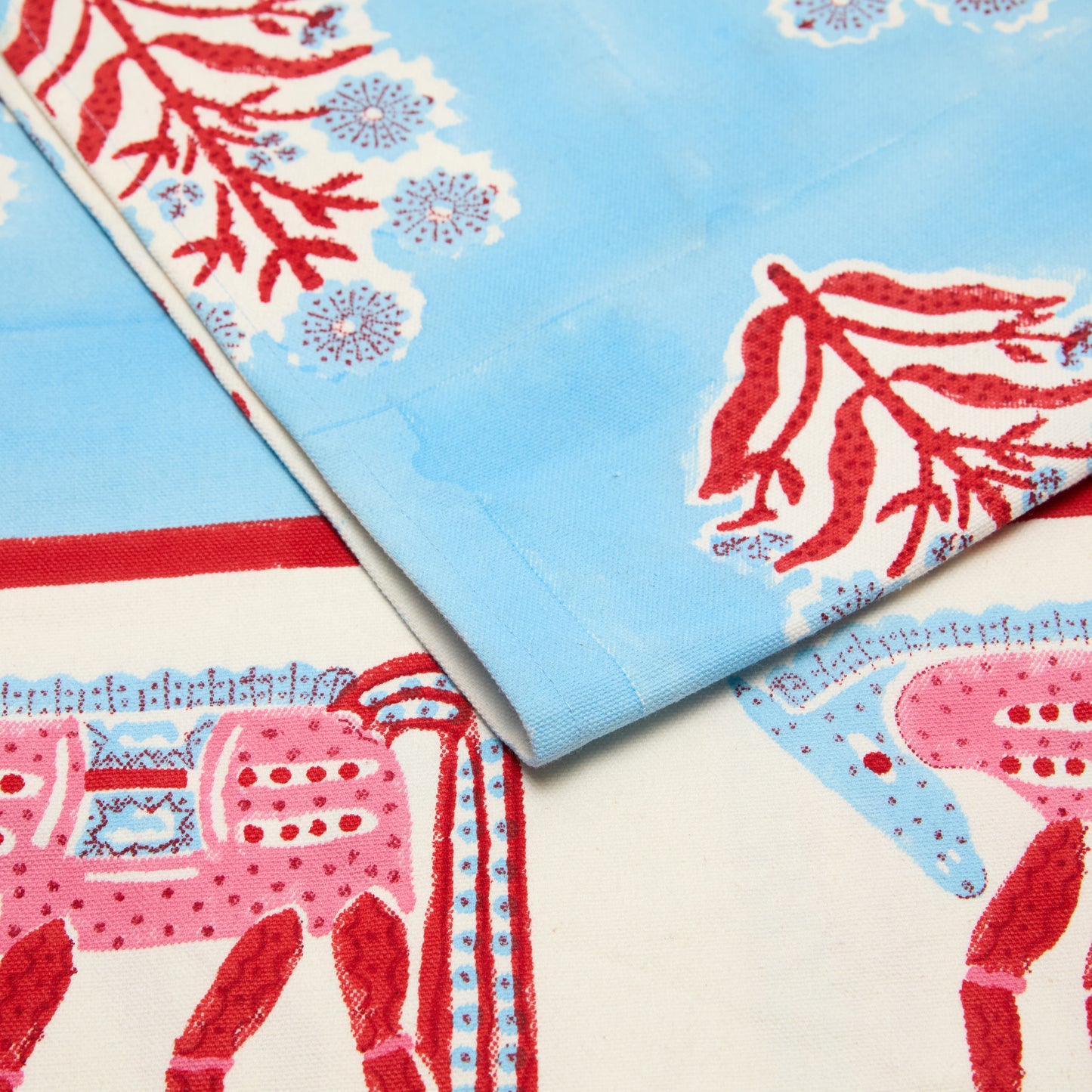 Blue and red block print cotton runner with floral motifs and horse border.