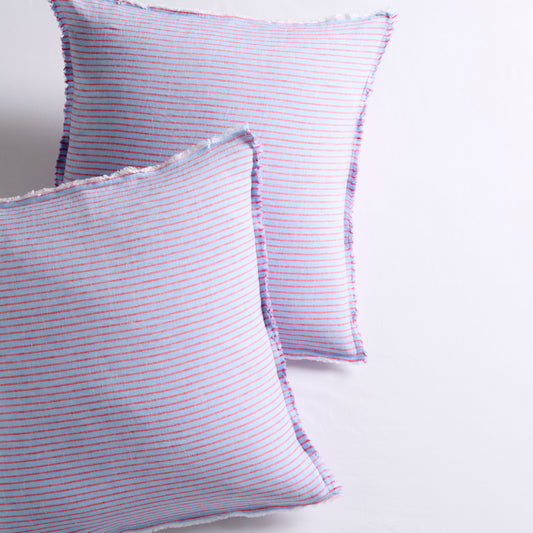 Two blue linen Euro shams with thin red stripes and frayed edges.