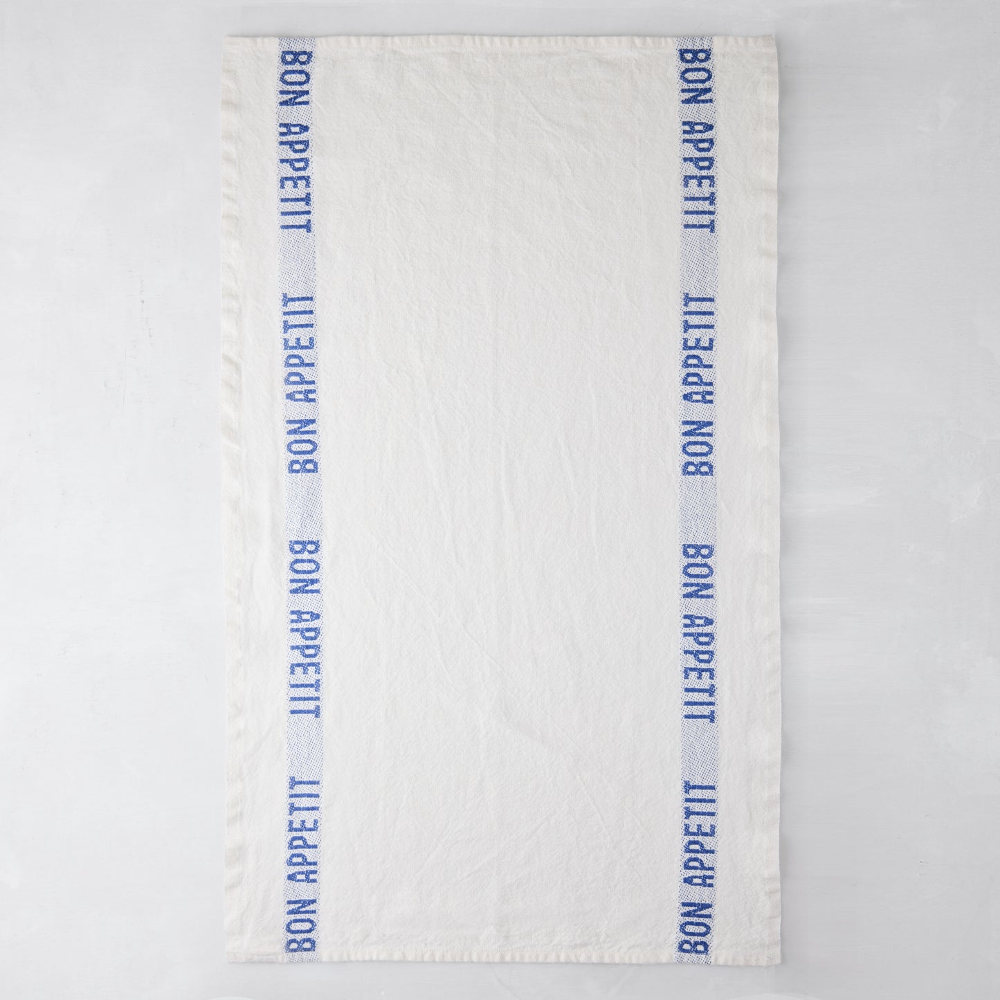 White linen hand towel with blue "Bon Appetit" text stripes on both sides.