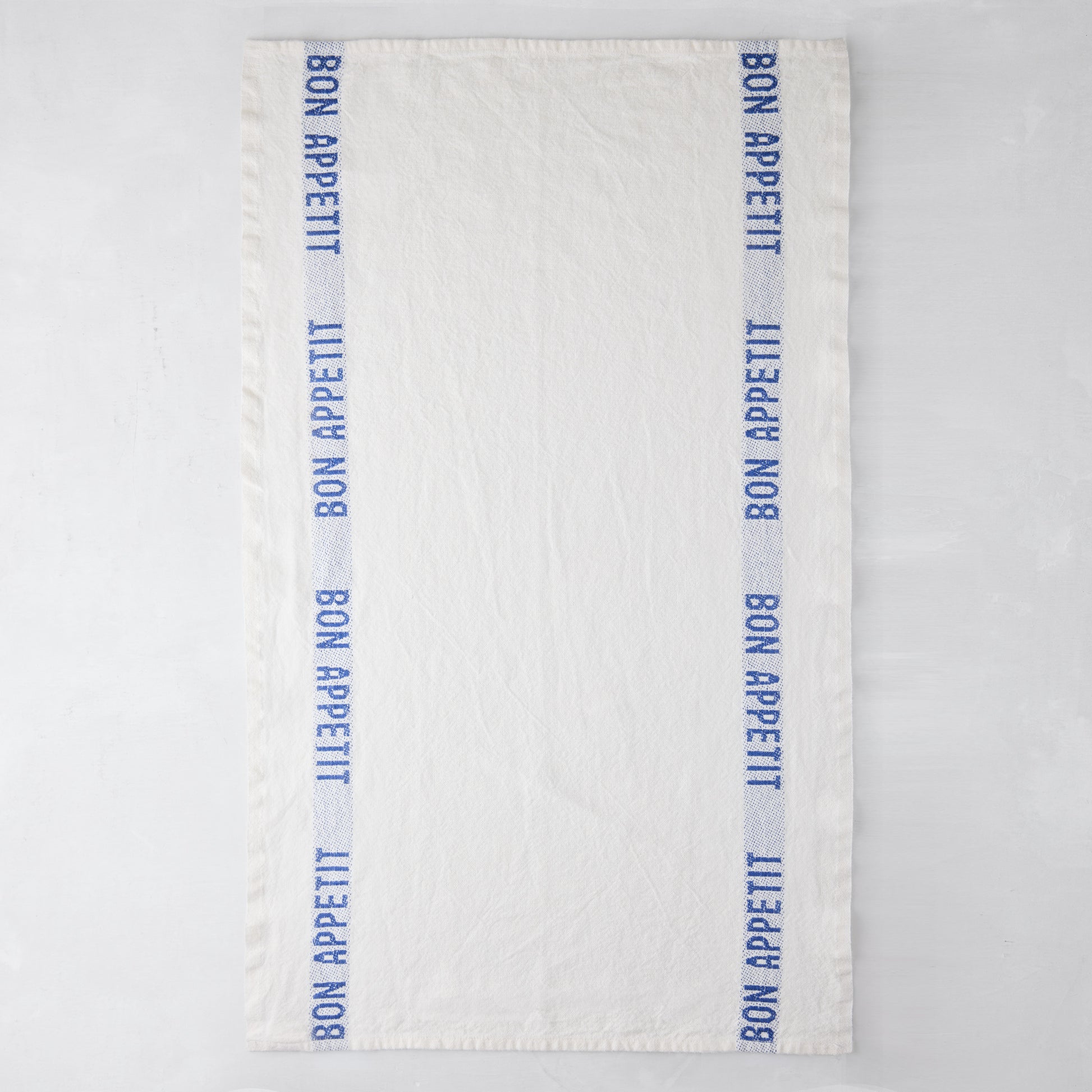 White linen hand towel with blue "Bon Appetit" text stripes on both sides.