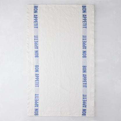 White linen hand towel with blue "Bon Appetit" text stripes on both sides.