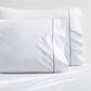 Set of 2 white percale pillowcases with blue diamond embroidered detail.