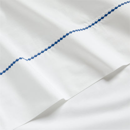 White percale sheet set with a blue diamond embroidered detail.