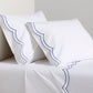 White organic cotton percale sheet set with blue double scallop stitch embroidery on pillows and flat sheet.