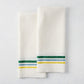 Set of 2 white cotton-linen hand towels with blue, green, and yellow triple stripes.