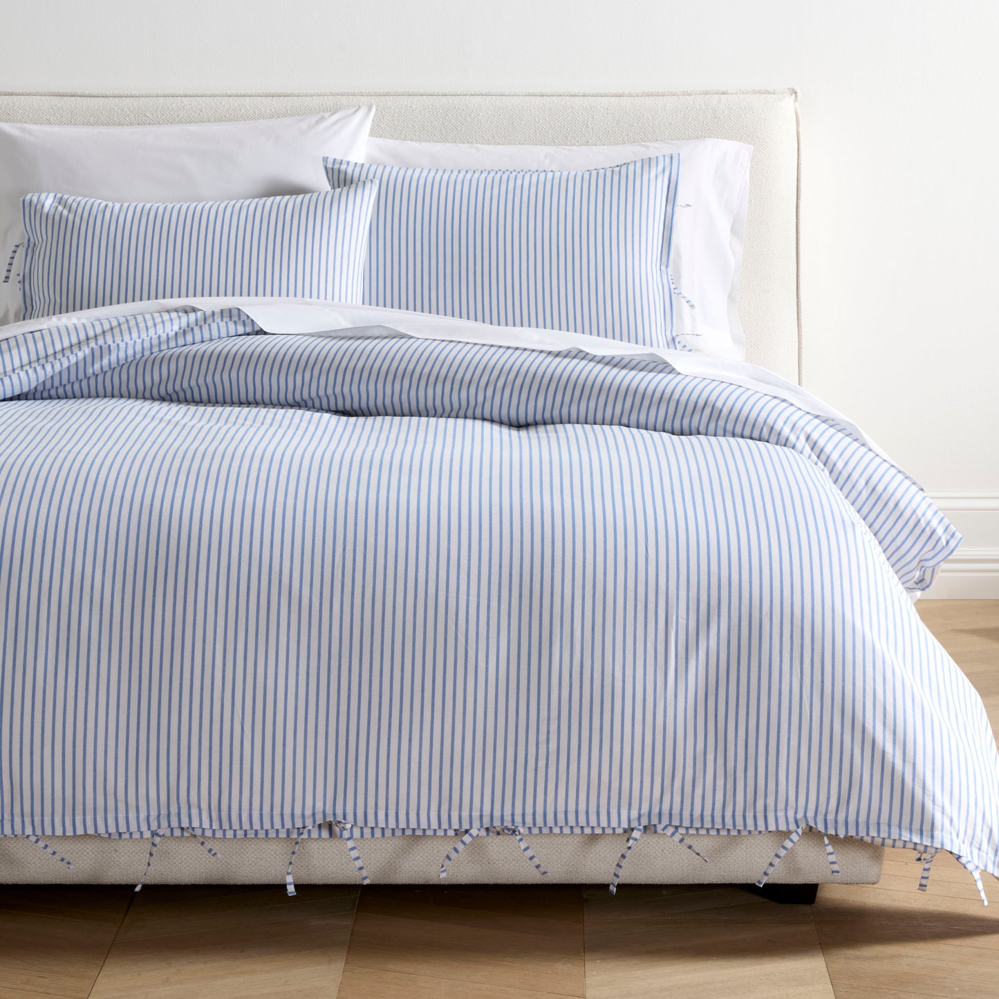 Blue Oxford Thin Stripe Cotton Duvet and Shams Set with tie closures on a bed.