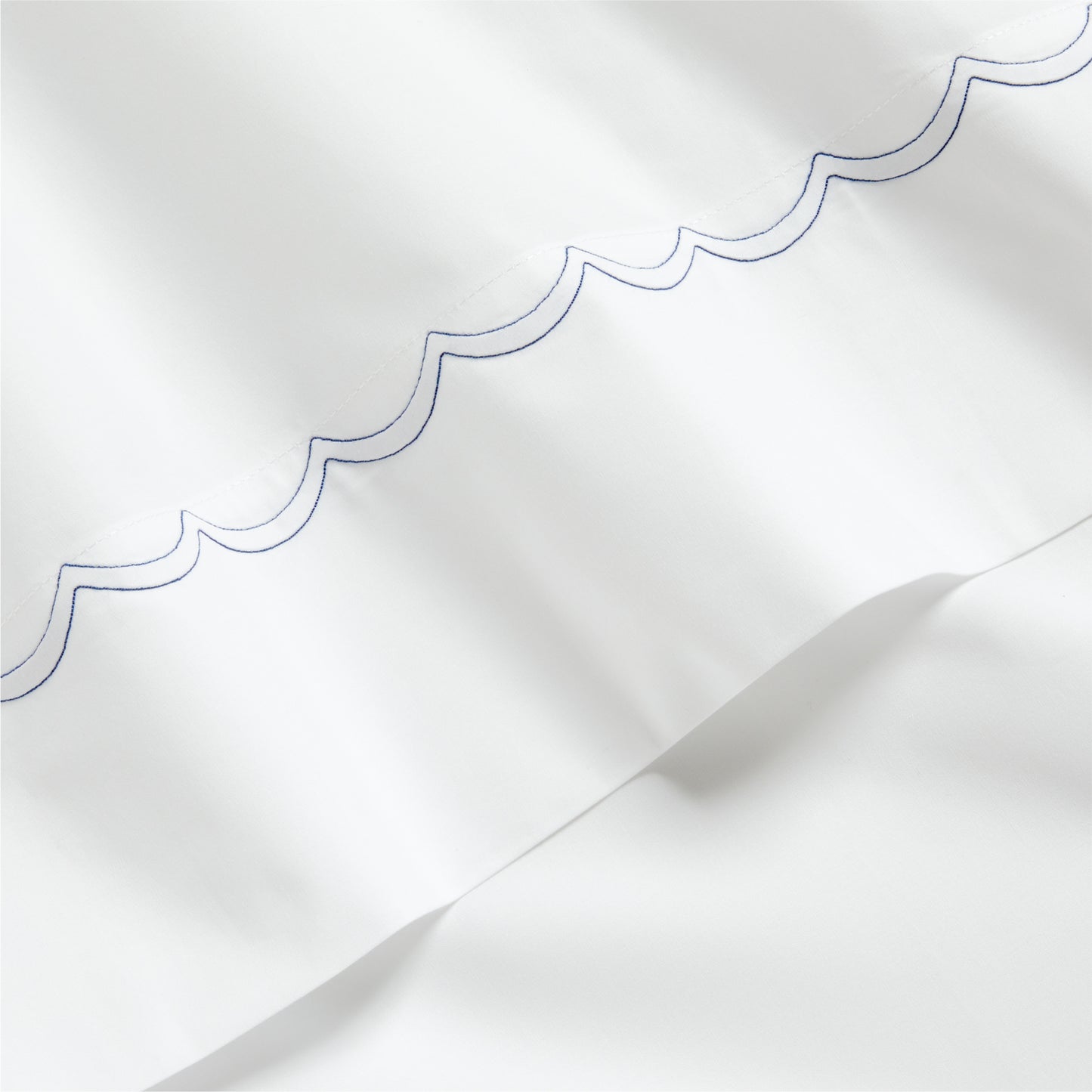 White percale sheet with a blue scallop-stitch detail along the edge.