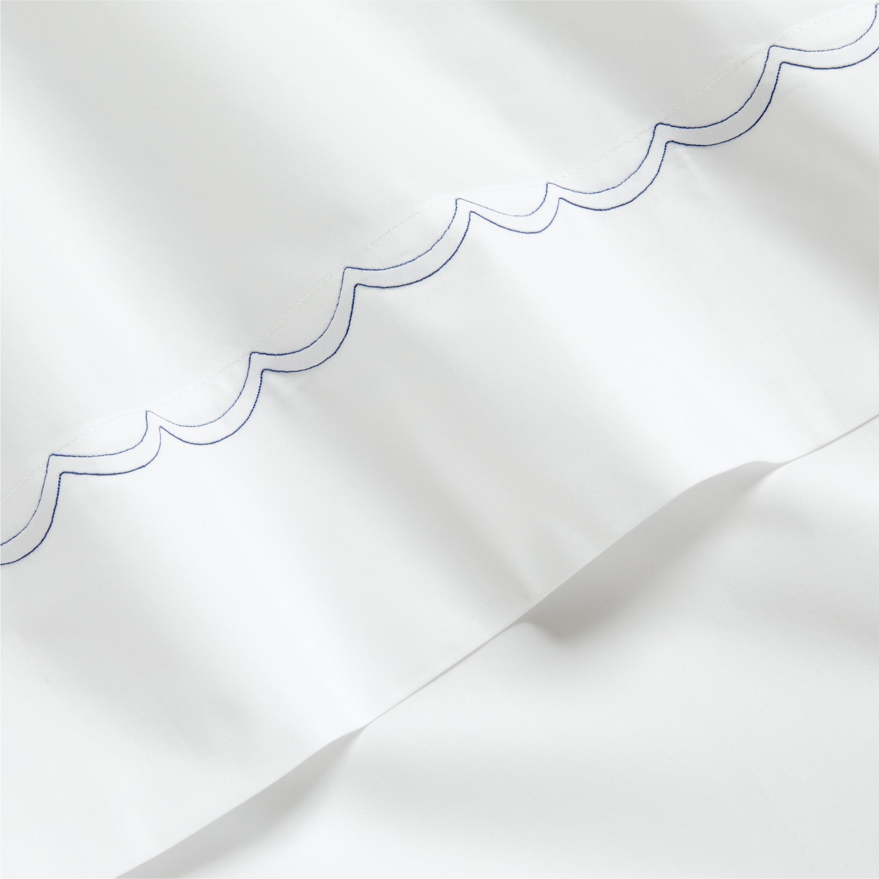 White percale sheet with a blue scallop-stitch detail along the edge.