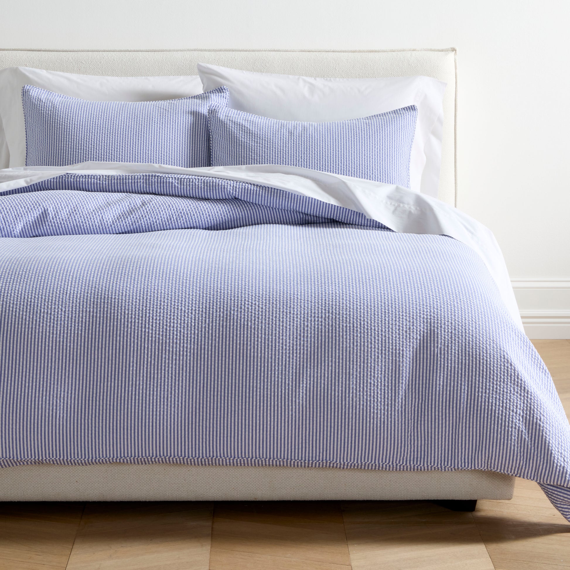 Blue seersucker stripe organic cotton duvet cover and two shams on a bed.