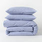Blue seersucker stripe organic cotton duvet cover and two shams, folded and stacked.
