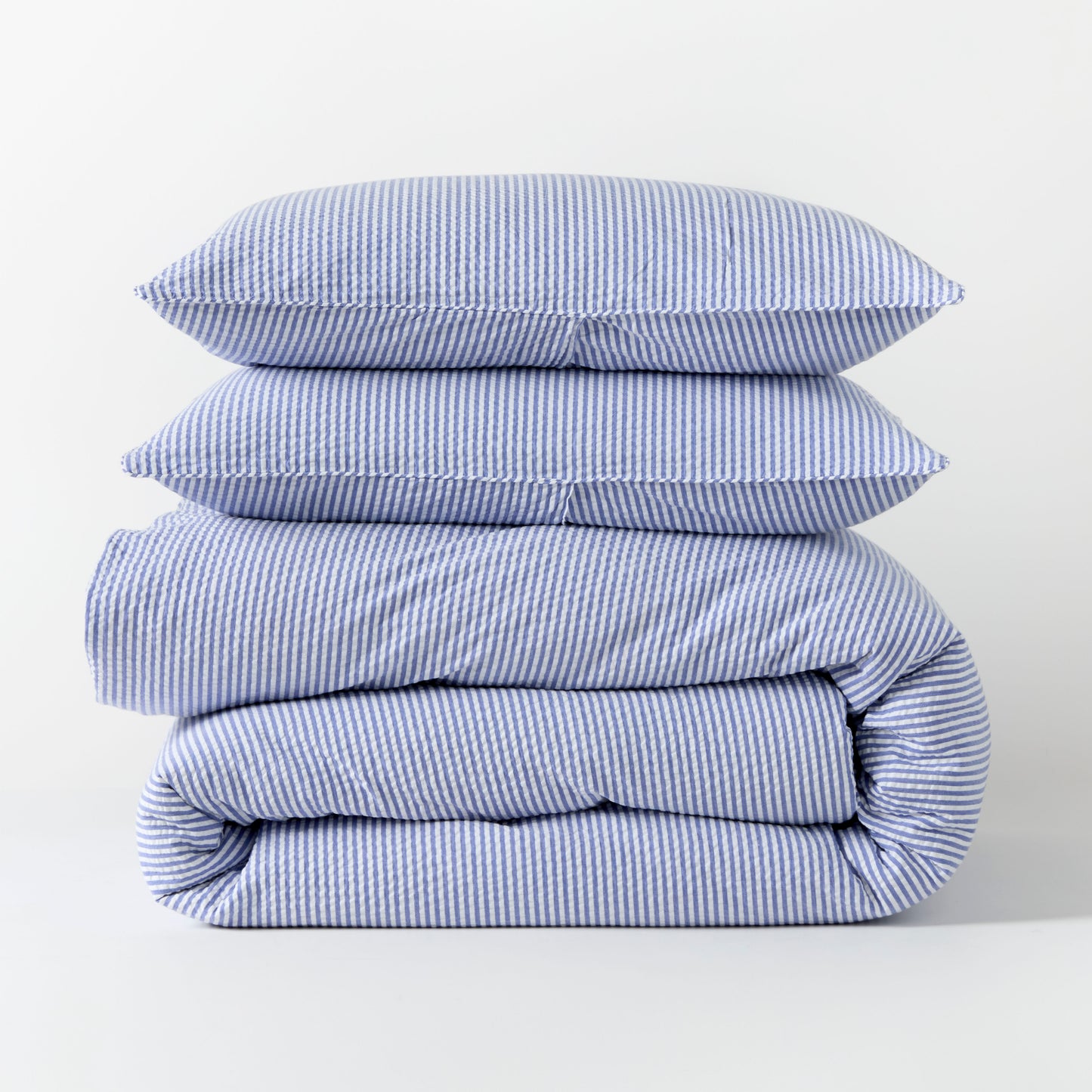 Blue seersucker stripe organic cotton duvet cover and two shams, folded and stacked.