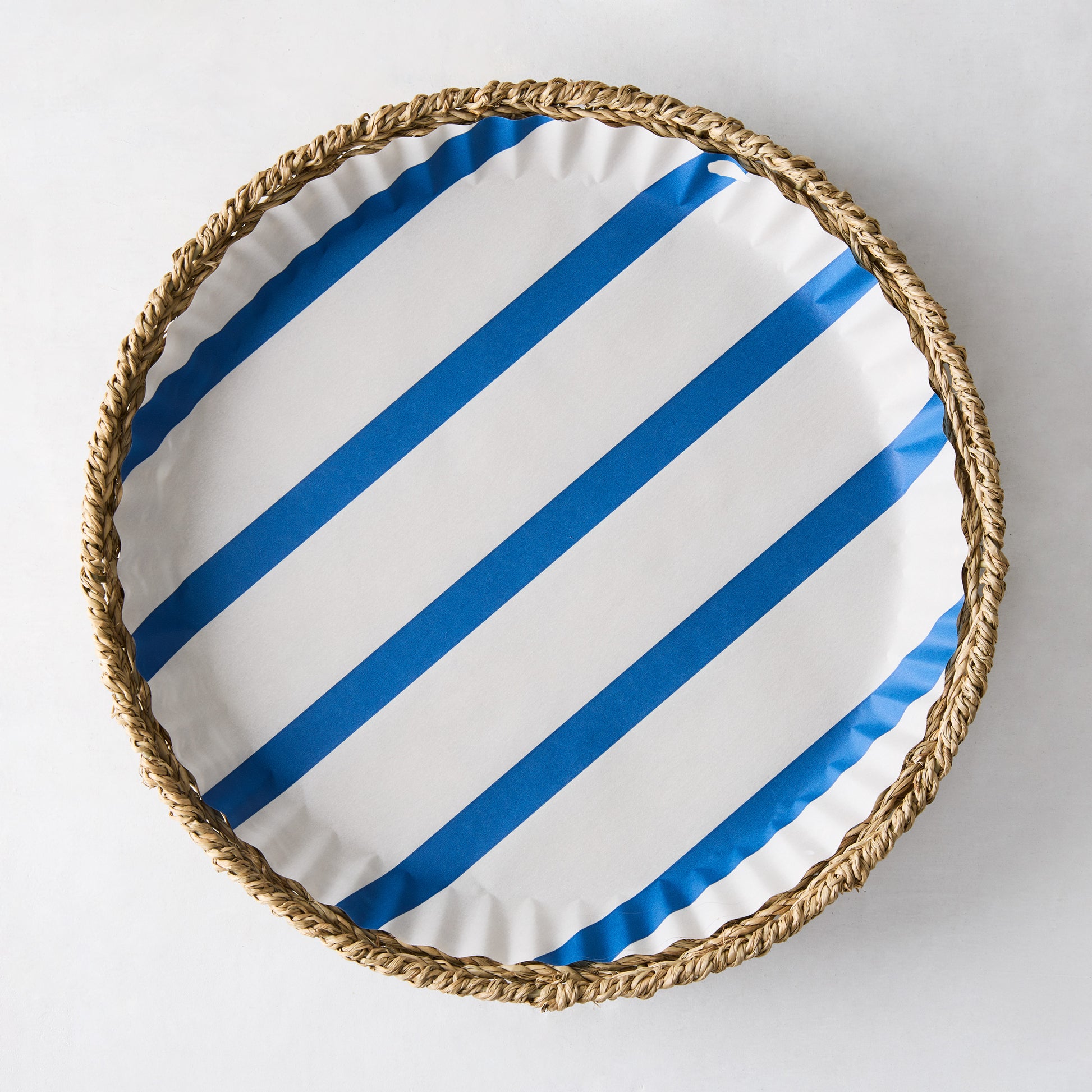 Round parchment liner with blue diagonal stripes in a woven straw basket.