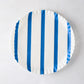 Round white parchment liner with vertical blue stripes and ruffled edges.
