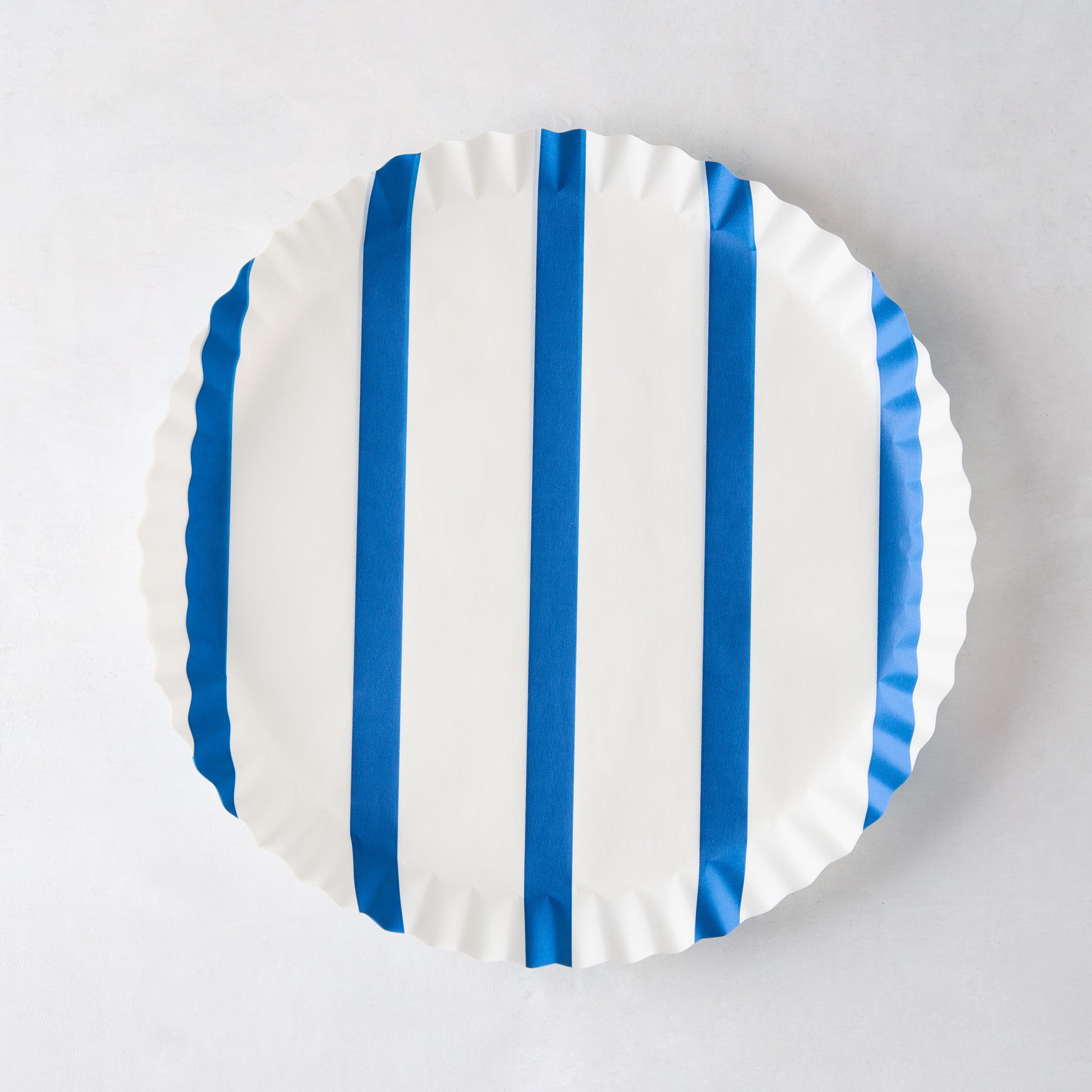 Round white parchment liner with vertical blue stripes and ruffled edges.