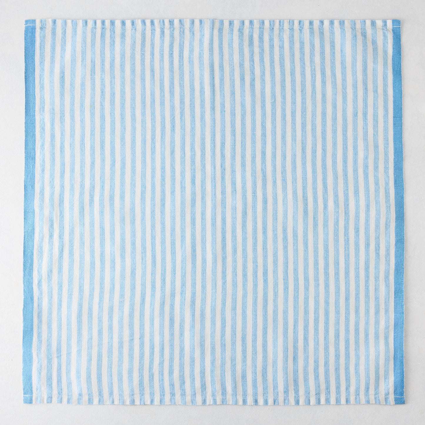Blue Ticking Stripe Linen Napkin, 21" square, with thin light blue and white vertical stripes and a thicker blue border.