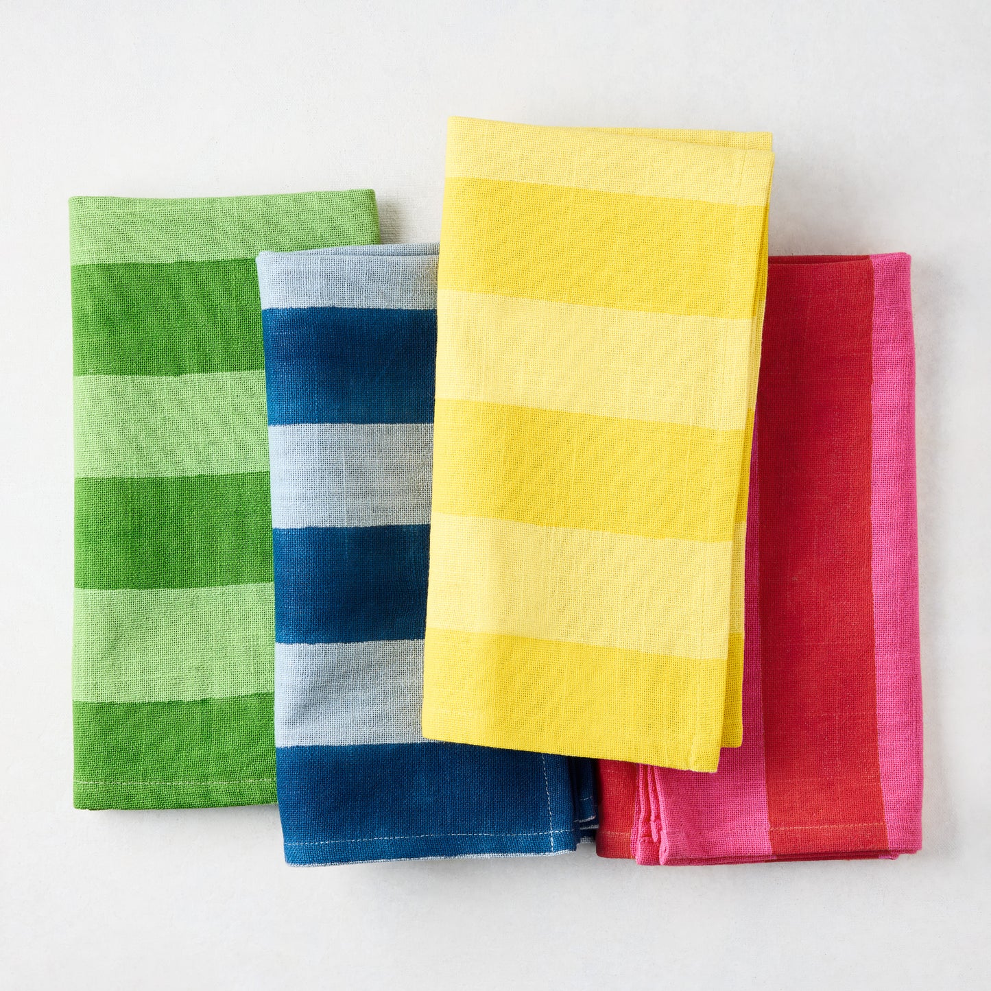 Four folded cotton napkins: green, blue, yellow, and red, all with tonal Hampton stripes.