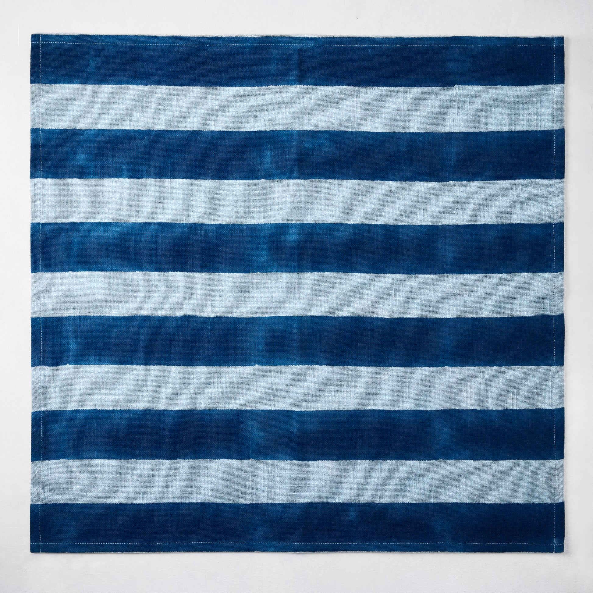 Blue Tonal Hampton Stripe Cotton Napkin, 22" square, with bold and light blue horizontal stripes.